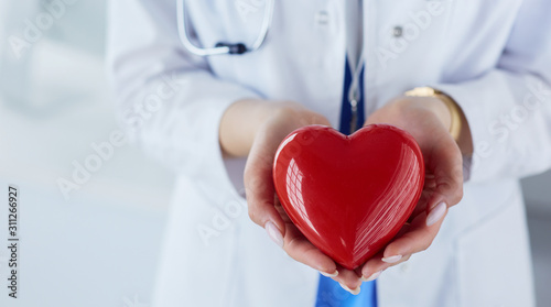 Cuadros en Lienzo Female doctor with stethoscope holding heart, on light background