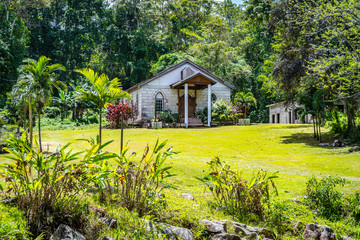 Small modest old brick wall chapel, built in 1903, in a Caribbean island countryside. All Saints Anglican Church in Chester Castle town, Hanover parish, Jamaica, surrounded by lush green landscape.