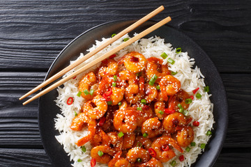 Wall Mural - Fried sticky shrimps with garlic, chilli, sesame seeds and green onions served with rice close-up in a plate. Horizontal top view