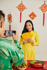 Poster - Lovely young Vietnamese woman in traditional yellow dress posing for photo at Lunar New Year celebration