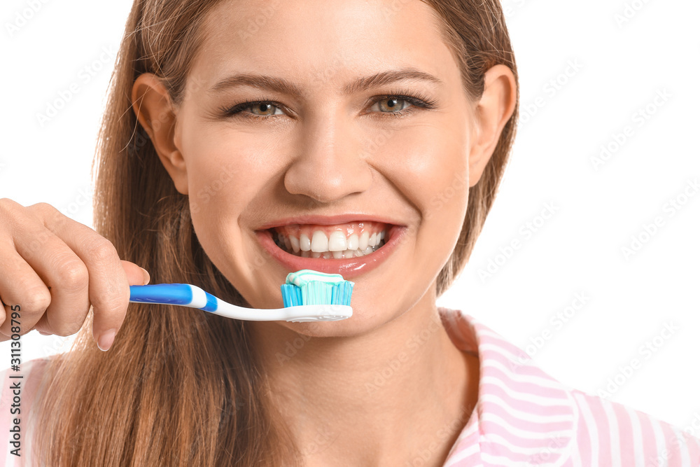 Young woman brushing teeth on white background