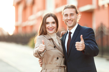 Wall Mural - Young couple showing thumb-up gesture near their new house