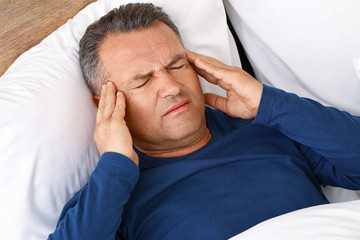 Poster - Mature man suffering from head ache while lying in bed