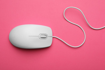 Wired computer mouse on pink background, top view