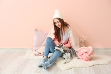 Wall Mural - Young woman with funny husky puppy sitting near color wall