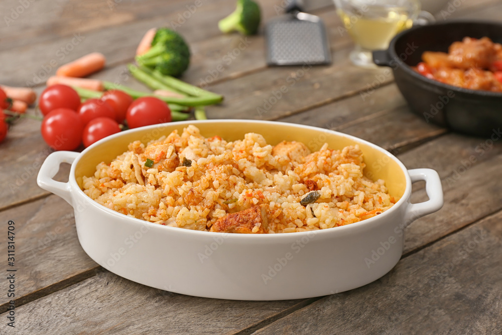 Dish with tasty rice on wooden table