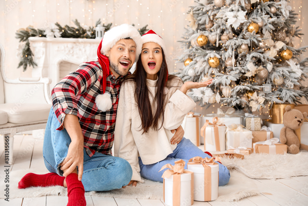 Surprised couple with Christmas gifts at home