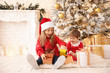 © Pixel-Shot - Little children opening Christmas gifts at home