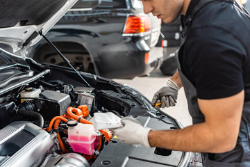 partial view of mechanic wiping oil dipstick with rag near car engine compartment