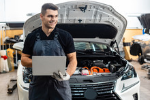 Handsome Mechanic Holding Laptop While Standing Near Car With Open Hood