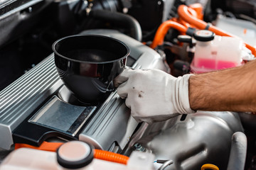 Wall Mural - cropped view of mechanic holding oil funnel near car engine