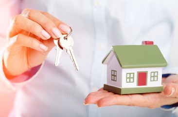 Canvas Print - Human hand holds metal keys and mini house