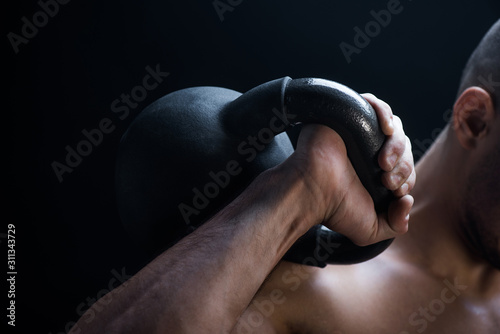 Cuadros en Lienzo cropped view of muscular bodybuilder excising with kettlebell isolated on black