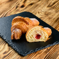 Wall Mural - cut croissant with filling on a wooden rustic background