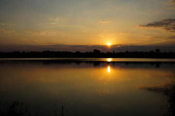 Wall Mural - Sunset in the river or dam with reflected light water,silhouetted tree and beautiful sky in the evening.