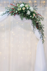 marriage flower composition with chrysanthemum, rose, pistachio, thuja, waxflower, ilex, eustoma, eucalyptus parvifolia, pine branch on arch for winter wedding decoration, closeup stock photo image