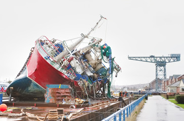 Wall Mural - Capsized ship vessel and rescue lift crane at port dock for repair of shipwreck