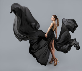 beautiful young girl in flying black dress. Flowing fabric. Light black fabric flying in the wind