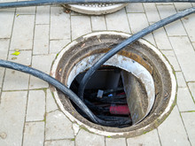 Open Manhole For Cable Replacement On The Sidewalk. Laying Of New Cables In A Hatch On A Pavement. Underground Construction And Repair. Inside Of Manhole.