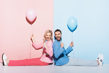 Wall Mural - back to back view of smiling woman and handsome man with balloons showing yes gesture on pink and blue background