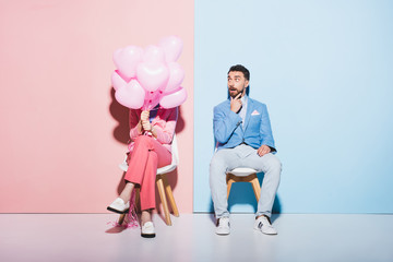 Wall Mural - woman holding balloons and shocked man on pink and blue background