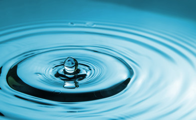 Closeup Water drop falling on the surface of the water and beautiful circular wave ripple, fresh natural mineral water drink water concept