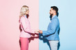 © LIGHTFIELD STUDIOS - side view of smiling woman and handsome man holding hands on pink and blue background