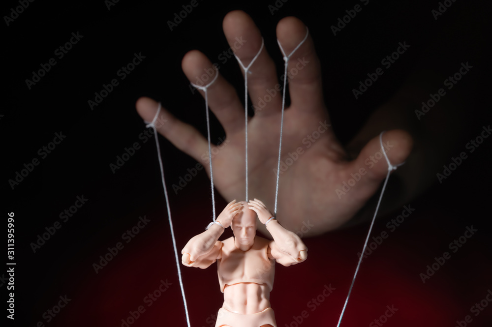 Concept of control. Marionette in human hand. Objects are colored on red and blue light. - obrazy, fototapety, plakaty 
