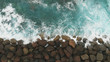 canvas print picture - Top down view. The construction of stones to strengthen and protect the coast from the ocean - a bird's-eye view. Large stones and the ocean of turquoise color.