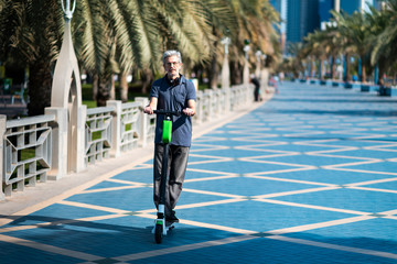 Senior using electric scooter for transportation in a modern city