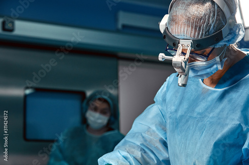 Fotografía Close up portrait of young female surgeon doctor wearing protective mask and hat during the operation