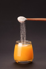 Orange juice with spoon of protein or collagen. Food supplement concept