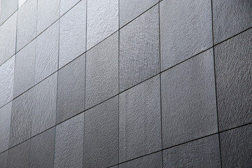 Poster - Abstract modern architecture and construction or finishing material background of tiled granite wall. Minimalist building exterior or interior with geometric structure viewed in diagonal perspective.