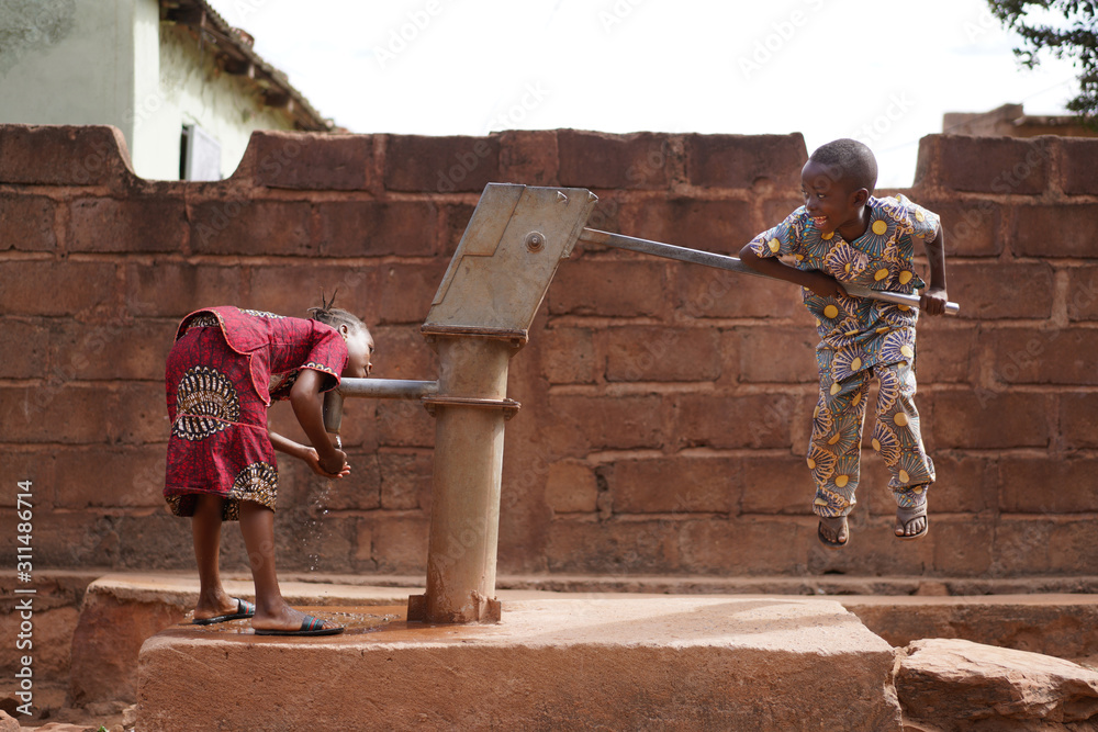 Small African Boy Trying to Pump Water from the Village Well - obrazy, fototapety, plakaty 