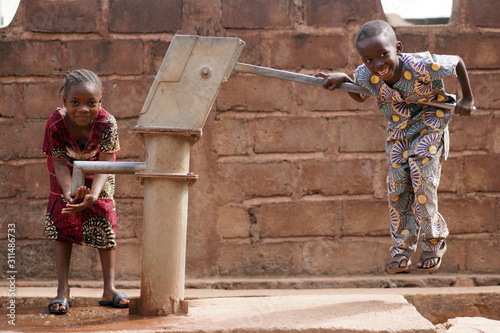 Photographie Happy Little African Boy Pumping Water For His Sister