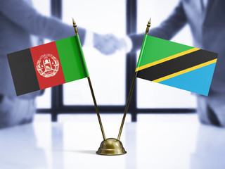 Wall Mural - Tanzania and Afghanistan mini table flags on white wooden desk. Diplomatic background with men shaking hands, international relations and agreements.