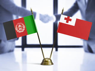 Wall Mural - Tonga and Afghanistan mini table flags on white wooden desk. Diplomatic background with men shaking hands, international relations and agreements.