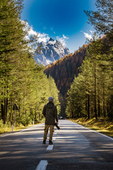 Young male photographer from behind taking pictures of dolomites in Italian alps /  Dolomite mountains in background during sunny day / High ISO image