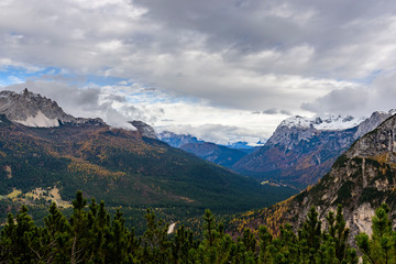 Colourful forest and Dolomite mountains surrounded by clouds in South Tyrol, Italy /View from Lago di Sorapis hiking trail / High ISO image