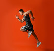 © New Africa - Athletic young man running on red background, side view