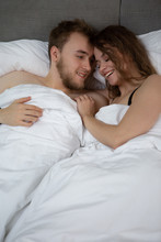 A Satisfied Man Looks At A Shy And Modestly Smiling Girl With Whom He Lies In The Same Bed