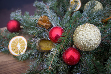 Bright Christmas balls and and decoration of oranges on fir branches on a wooden background.