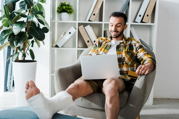 Wall Mural - selective focus of happy injured man holding credit card while online shopping at home