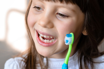 Wall Mural - Beautiful smiling preschool girl with her first adult incisor tooth. Cute child showing her baby milk tooth fell out  and her growing permanent tooth in open mouth. Dental hygiene concept