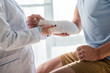 cropped view of orthopedist touching injured arm of man
