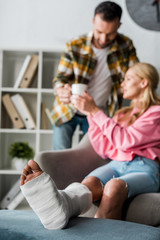 Wall Mural - selective focus of injured woman near handsome man with cup of tea