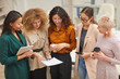 © Seventyfour - Group of five women talking about work during coffee break standing together in office room