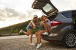 © BalanceFormCreative - Group of female best friends on travel . They sitting on car trunk and relaxing after long journey.