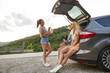 © BalanceFormCreative - Group of female best friends on travel . They sitting on car trunk and relaxing after long journey.