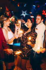 Group of friends having fun and holding sparklers at New Year's party